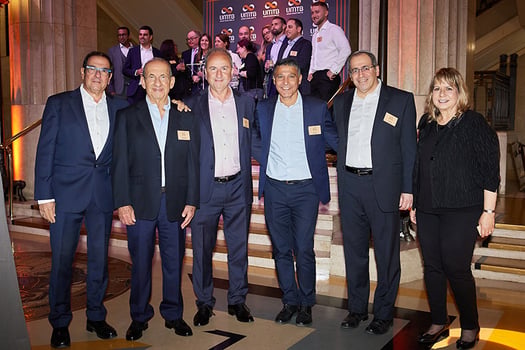 מימין: רחלי פרידמן, אופיר מורד, משה לארי, איציק קוריאט, משה וידמן ואריק בנדל. ברקע: עובדי השלוחה. צילום: מזרחי טפחות 